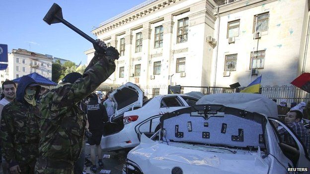 A protester smashes a car during a rally near the Russian embassy in Kiev - 14 June 2014