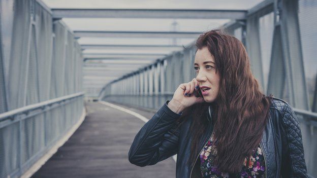 Young woman on phone on a bridge