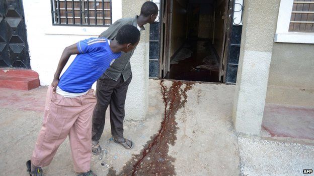 Men look at a pool of blood at the entrance of a restaurant in Mpeketoni. Photo: 16 June 2014