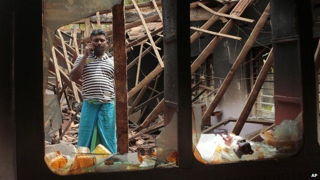 A Sri Lankan Muslim man talks over his mobile phone as he stands among the debris of his charred house, in Aluthgama, town, 50 kilometres (31 miles) south of Colombo, Sri Lanka, Monday, June 16, 2014.