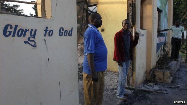 Residents of Kibaoni look at the ruins of the burnt down Breeze View Hotel after unidentified gunmen attacked the coastal Kenyan town of Mpeketoni June 16, 2014.