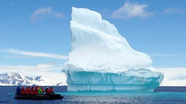 Tourists view an iceberg in Kinnes Cove