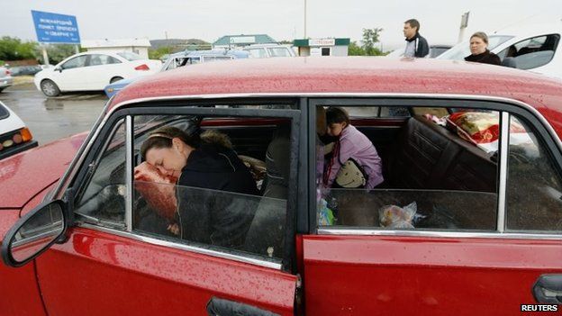 A woman and a child rest inside their car as they wait in a queue to leave Ukraine