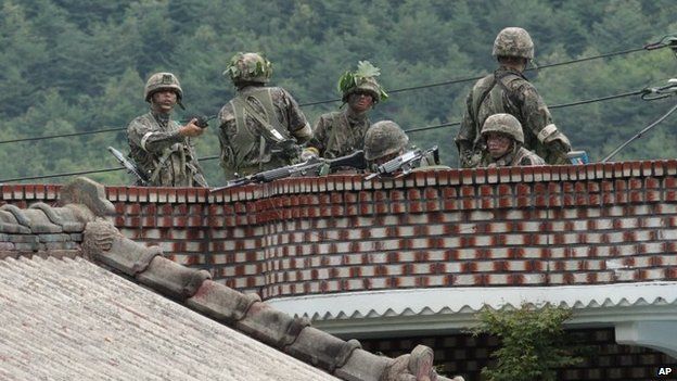Солдаты южнокорейской армии занимают позицию на крыше частного дома в поисках южнокорейского солдата-срочника, который скрывается после перестрелки в Госоне, Южная Корея, 22 июня 2014 г.