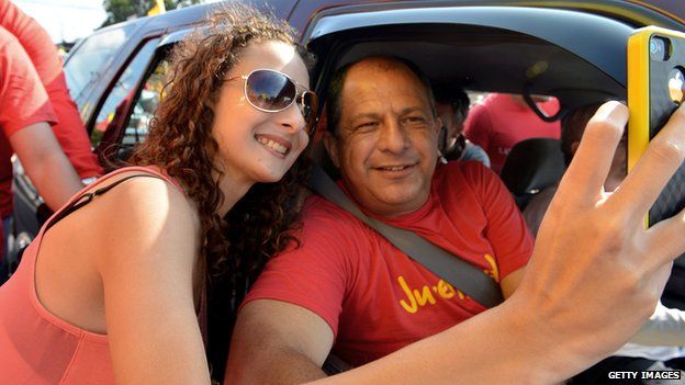 Luis Guillermo Solis takes a picture with a supporter along the streets of Coronado on 30 March, 2014