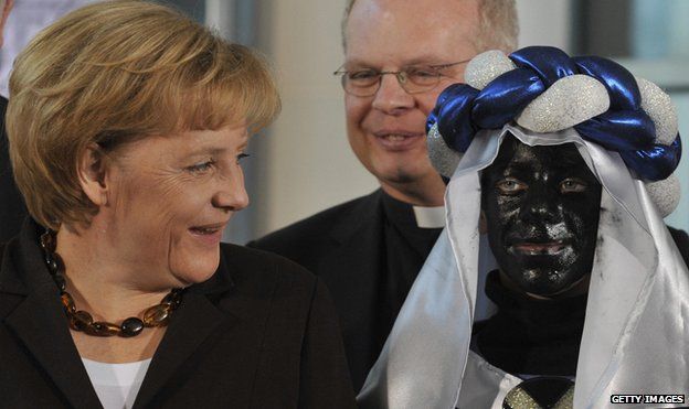 Angela Merkel and a child with a blacked up face on the Three Kings Day