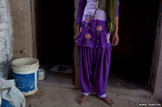 Santraj's daughter stands outside the family's toilet