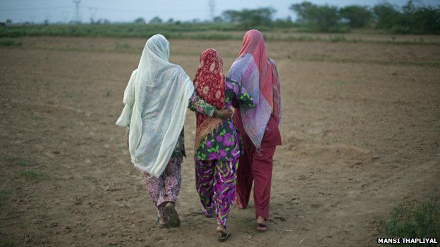 Women walking away from camera in Indian field
