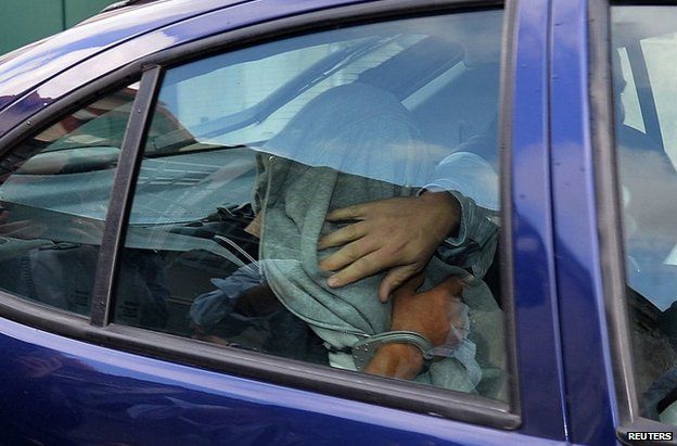 The masseuse of the prominent Pastor family, hidden under a jacket, leaves a police station in a police car during a transfer from Nice to the courthouse in Marseille June 27