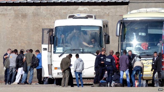 Migrants being put onto a bus after being ejected from their camp in Calais