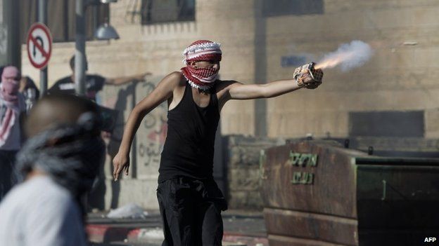 A Palestinian youth directs fireworks at Israeli riot police in East Jerusalem (2 July 2014)