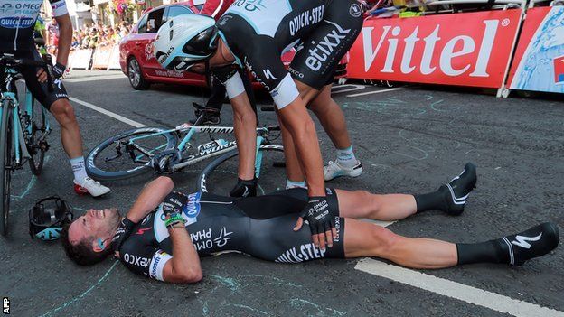 Cavendish lies injured as an Omega Pharma - Quick-Step team-mate looks over him