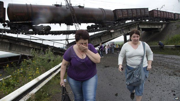 People walk under a destroyed railroad bridge over a main road leading into Donetsk, near the village of Novobakhmutivka, 20km north of Donetsk, eastern Ukraine (7 July 2014)
