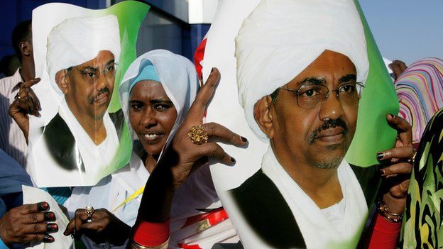 Supporters of Sudanese President Omar al-Bashir hold his pictures as they wait to greet him at Khartoum airport on 14 November 2012