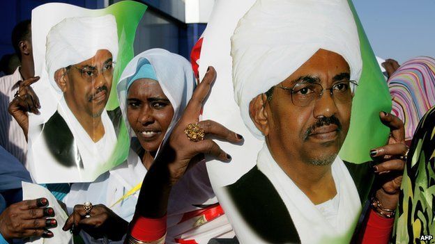 Supporters of Sudanese President Omar al-Bashir hold his pictures as they wait to greet him at Khartoum airport on 14 November 2012