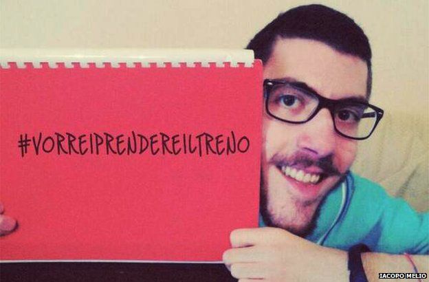 Iacopo Melio holds up a sign saying "#VorreiPrendereilTreno", which means "I would like to take the train"