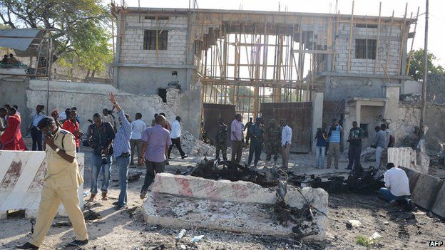 File photo: Onlookers and a Somali soldier stand amid the debris after an attack in front of the presidential palace in Mogadishu, 21 February 2014