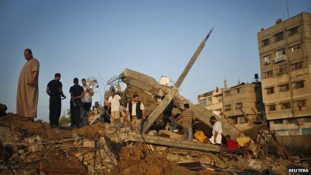 Palestinians in Gaza City survey the rubble of a house targeted in an Israeli air strike, 9 July