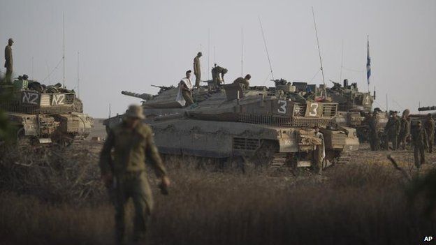 Israeli soldiers work on their tanks at a staging area near the Israel-Gaza Border, 9 July