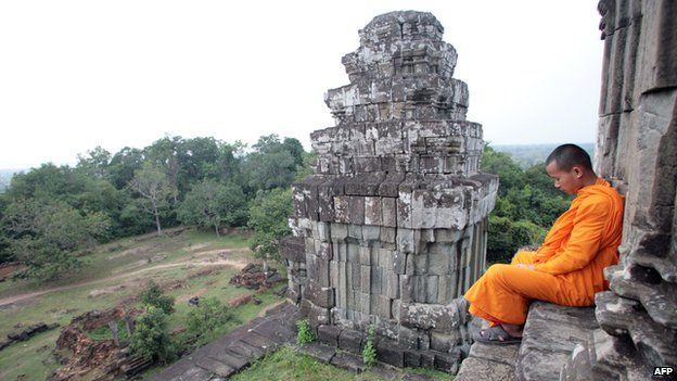 Monk sits on stairs at the Bayon Temple in Angkor, Cambodia
