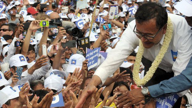 Sam Rainsy, the leader of opposition Cambodia National Rescue Party (CNRP), shakes hands with supporters at Democracy Park during the general election campaign in Phnom Penh on 26 July 2013.