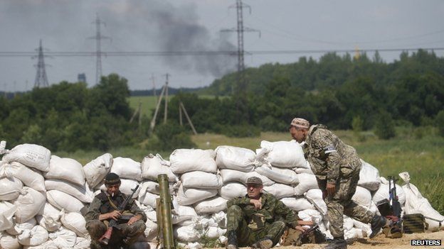 Pro-Russian separatist fighters from the so-called Battalion Vostok (East) wait behind a sandbag wall at a checkpoint on the outskirts of Donetsk on 10 July 2014