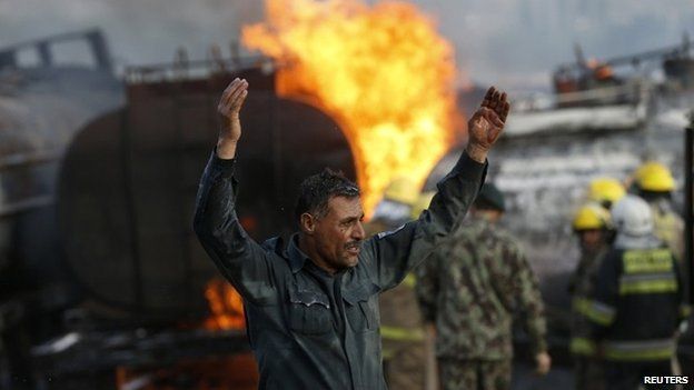 A policeman reacts at the site of burning fuel trucks after a overnight attack by the Taliban on the outskirt of Kabul July 5, 2014.