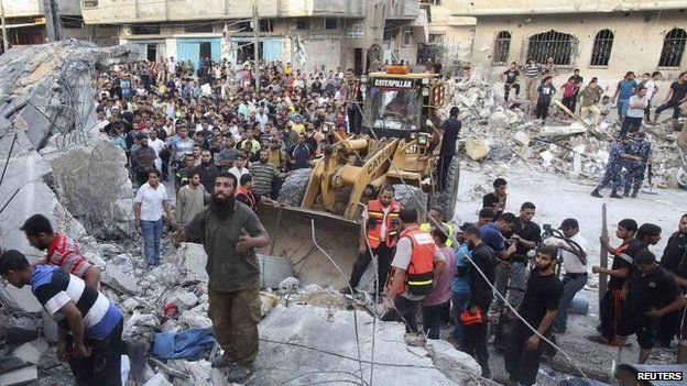 Palestinians search for anyone trapped in rubble in an overnight air strike in Rafah, 11 July