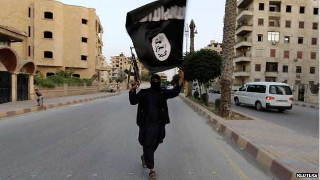 A member loyal to the Islamic State in Iraq and the Levant (Isis) waves an Isis flag in Raqqa, Iraq, 29 June 2014