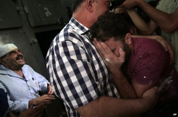 Palestinians mourn in a morgue in Gaza City, 12 July