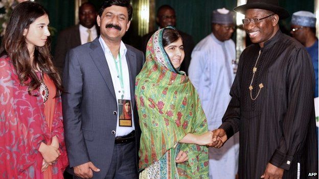 Pakistani education activist Malala Yousafzai (2nd R) shakes hands on 14 July 2014 with Nigerian President Goodluck Jonathan (R) next to her father, Ziauddin Yousafzai (2nd L), and Malala Fund committee member Shiza Shahid (L) at the State House in Abuja.