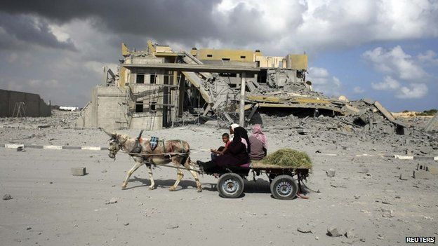 Palestinians ride a donkey cart past a damaged building in Rafah in the southern Gaza Strip July 15, 2014.