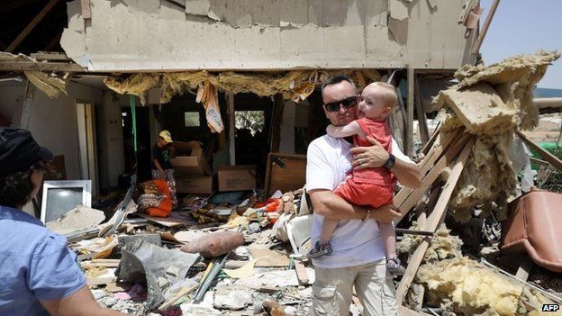 Residents of the southern Israeli city of Beersheba inspect the damage to a house in their city on July 12, 2014, after it was hit by a rocket fired during the night from the Gaza Strip