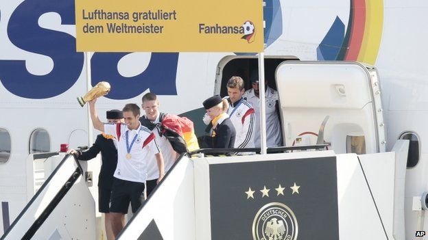 Members of the German team with the World cup in hand get off their plane after it arrived in Berlin