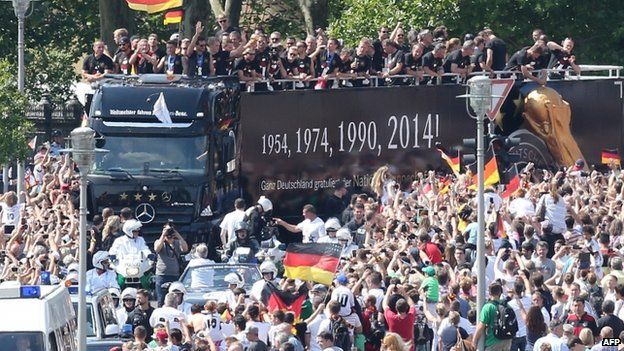 German fans cheer as the national team rides in an open-deck bus in central Berlin (14 July 2014)