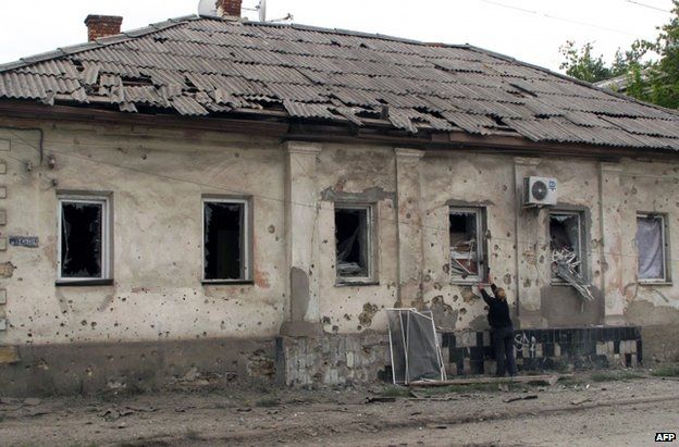 A woman boards up windows in her home in Luhansk after night fighting in the Ukrainian city, 15 July