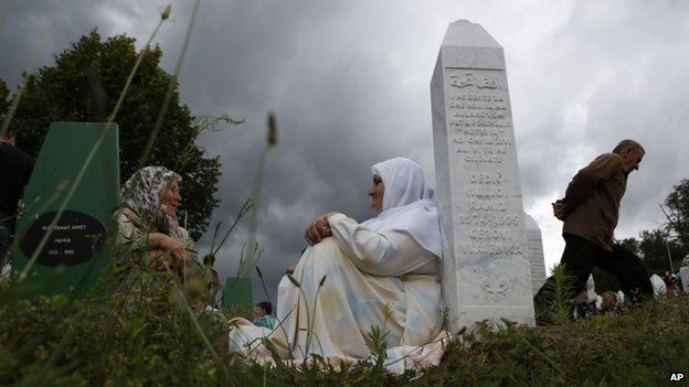 Bosnian Muslim women rest near a gravestone during a funeral in Srebrenica, Bosnia on 11 July 2014.
