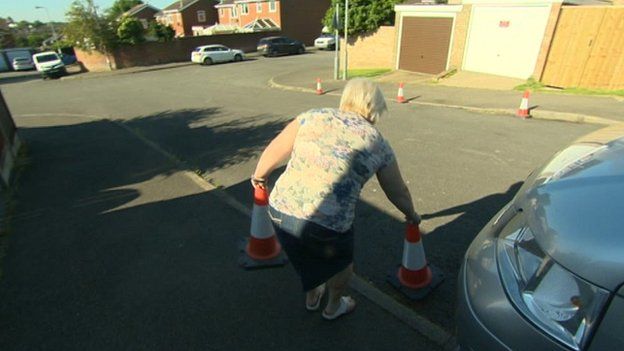 Woman putting traffic cones on road in Wellingborough