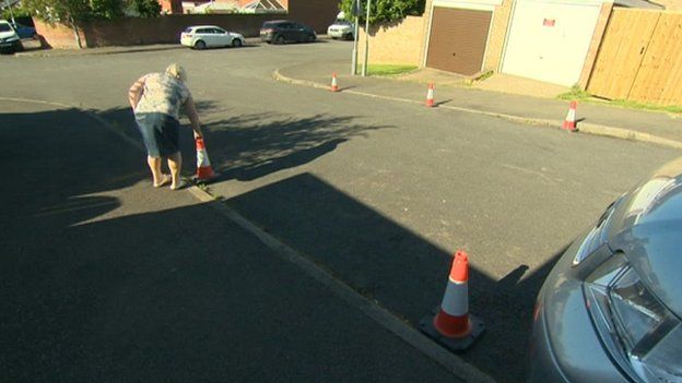 Woman putting traffic cones on road in Wellingborough