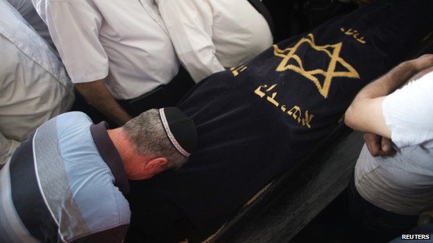 Relatives of Dror Khenin mourn next to his body during his funeral nea Tel Aviv, after Mr Khenin was killed on Tuesday (16 July 2014)