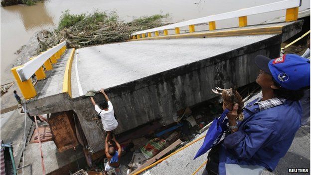 A resident climbs on a bridge destroyed during the onslaught of Typhoon Rammasun, (locally named Glenda) in Batangas city south of Manila, 17 July 2014.