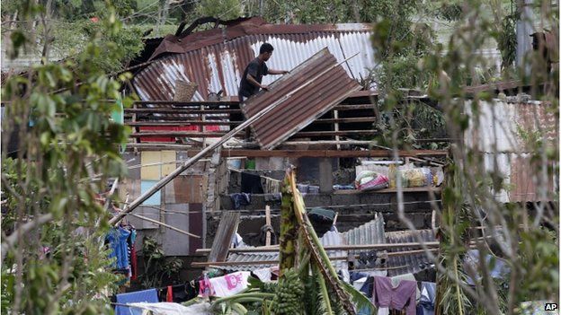 A resident fixes his house which was damaged by Typhoon Rammasun on Wednesday in Batangas city, south of Manila, Philippines, Thursday, on 17 July 2014.
