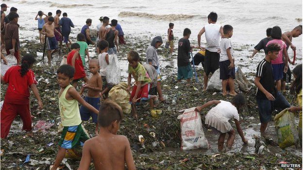 Residents gather salvageable items amidst debris brought at the onslaught of Typhoon Rammasun along the seashore of the coastal town of Rosario, Cavite southwest of Manila, on 16 July 2014.