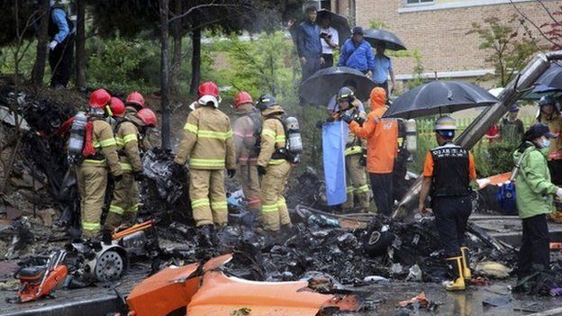 Firefighters inspect the wreckage of a helicopter which crashed near an apartment complex and school in Gwangju, South Korea, Thursday, on 17 July 2014.