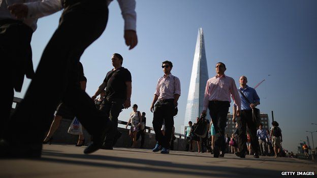 Pedestrians walking across a London bridge with Shard in background