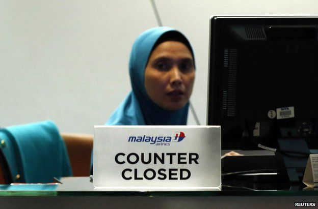A staff member sits behind a closed Malaysia Airlines desk at Kuala Lumpur International Airport, 18 July (local time)