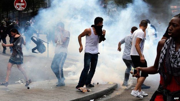 Protesters run to avoid tear gas near the aerial metro station of Barbes-Rochechouart, in Paris, 19 July 2014