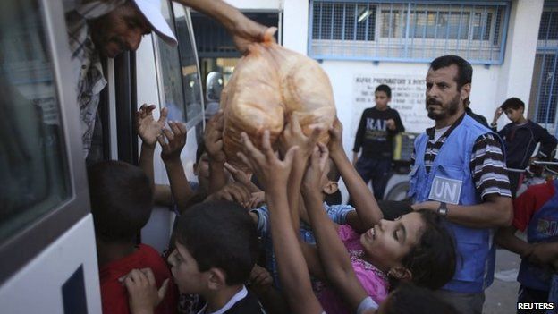 Palestinian children receive bags of bread from UN workers at a UN-run school in Rafah in the southern Gaza Strip, 19 July 2014
