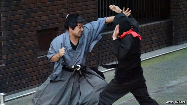 Samurai and ninja actors stage a fight on the streets of Tokyo