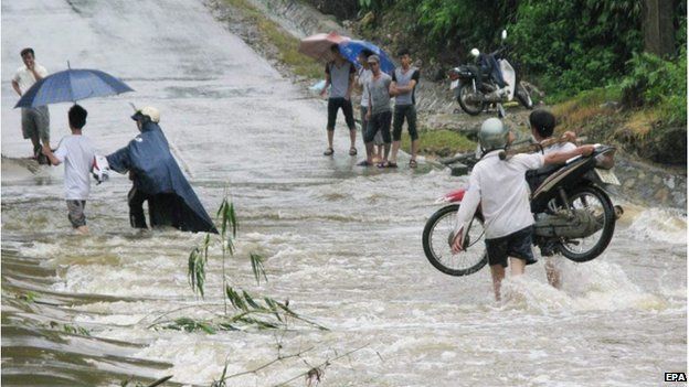 A photo made available 22 July 2014 shows people walk through a flooded area in Lao Cai, northern Vietnam, 21 July 2014.